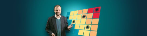 Mann im Business-Outfit vor einer farbigen Matrix aus Feldern mit Markierungspunkten, die eine Risikobewertung oder Entscheidungsstruktur visualisiert – Symbolbild für IT-Risikomanagement oder strategische Planung.